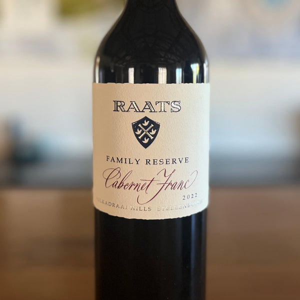 Bottle of Raats Family Reserve Cabernet Franc wine on a wooden surface with a blurred background